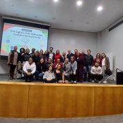 Grupo de pessoas em cima do palco, com painel sobre o ECA Digital ao fundo